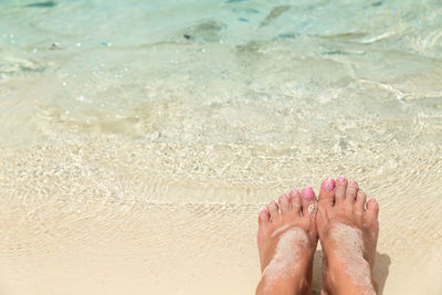 Low section of woman relaxing on sand at beach