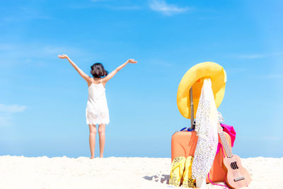 Woman with umbrella on beach against sky