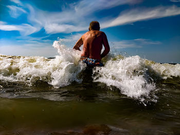 Man surfing in sea against sky