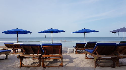 Chairs and tables on beach against sky