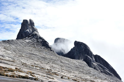 Low angle view of mountains against cloudy sky