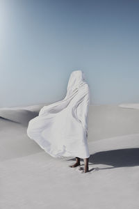 Side view of woman on bed against clear sky