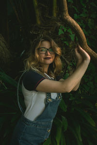 Portrait of young woman standing by tree