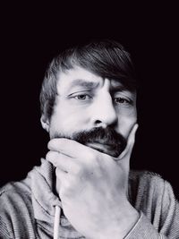 Portrait of young man against black background