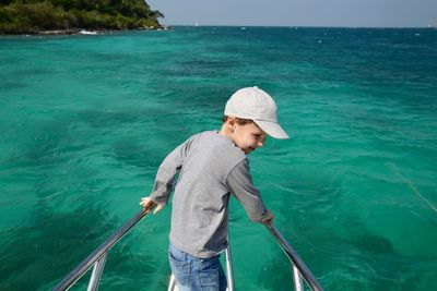 Boy standing in sea against sky