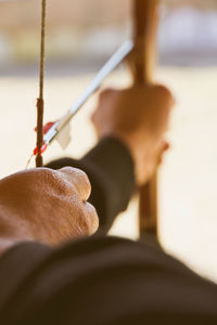 Cropped image of man with bow and arrow aiming at target