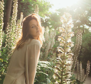 Portrait of woman standing by tree against plants
