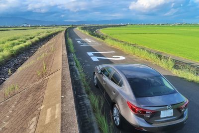 Panoramic view of road amidst field against sky