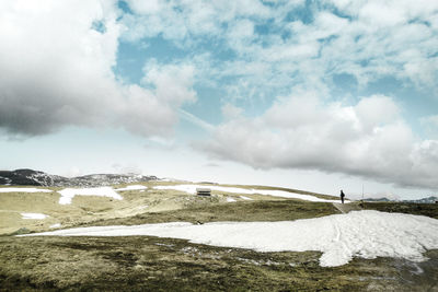 Scenic view of snowcapped mountains against sky with a man in deep hanging clouds