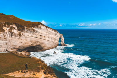 Rock formations by sea against blue sky