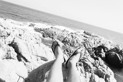 Low section of person relaxing on rocks at beach