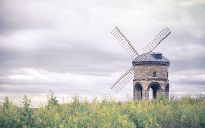 Traditional windmill on landscape against sky