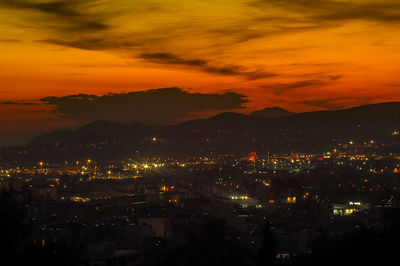 Illuminated cityscape against sky at sunset