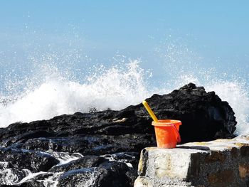 Water splashing on rock in sea with a child's bucket and spade 