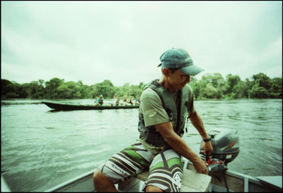 Full length of man holding boat in lake against sky