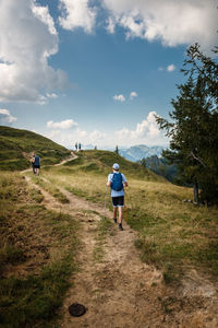 Rear view of man walking on trail against sky