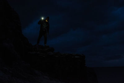 Full length of man standing on cliff at night