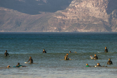 People enjoying in sea against mountains