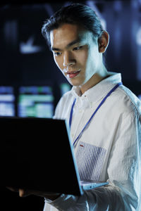 Portrait of young man using laptop at office