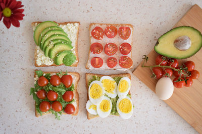 Healthy toast for breakfast with avocado, eggs, tomatoes, arugula etc