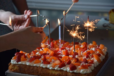 Close-up of hands lighting birthday candles