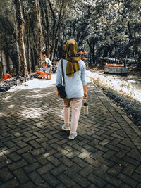 Rear view of woman walking on footpath