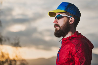 Man wearing cap and sunglasses standing outdoors