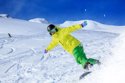 Low angle view of young man skiing on snowcapped mountains during winter