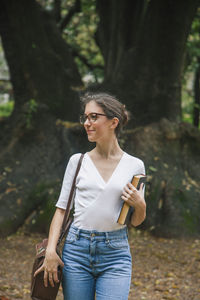 Young woman standing against trees in forest