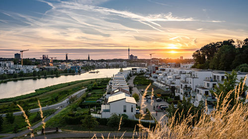 High angle view of buildings and river against sky at sunset