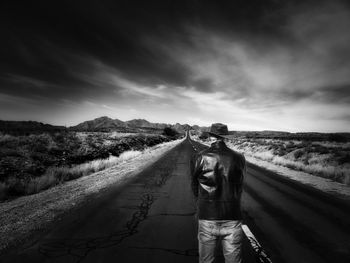 Rear view of man standing on road against sky