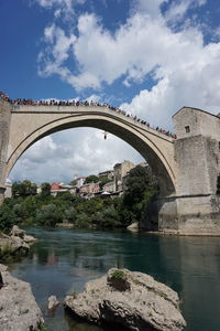 Arch bridge over river against sky