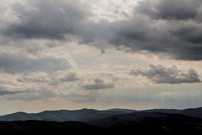 Scenic view of silhouette mountains against dramatic sky