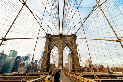 Brooklyn bridge by modern buildings against sky