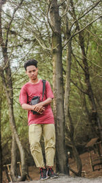 Young man standing against trees in forest