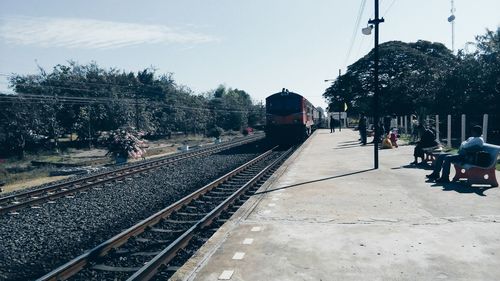 People waiting at railroad station platform against sky