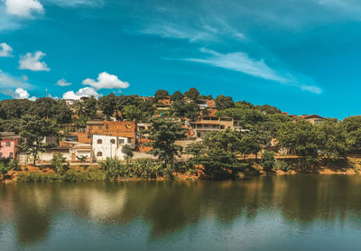 Scenic view of lake by buildings against blue sky