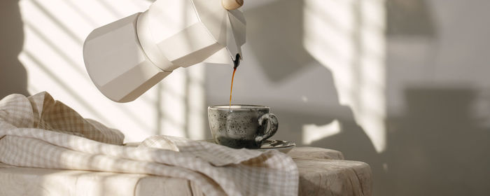 Close-up of hand pouring tea cup