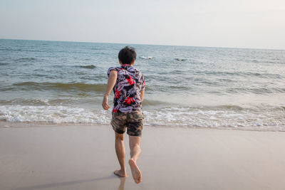 Rear view of woman on beach against sky