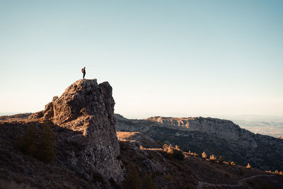 Man standing on rock looking at mountain against sky