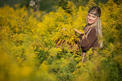 Young woman standing amidst plants on field