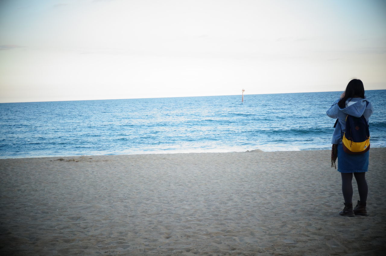 REAR VIEW OF PEOPLE STANDING ON BEACH