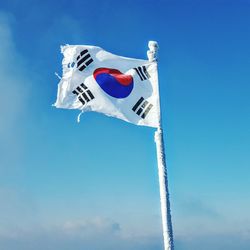 Low angle view of flag flags against blue sky