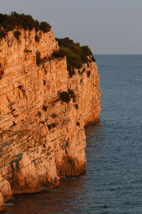 Rock formations by sea against clear sky