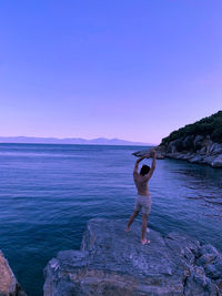 Rear view of man standing on rock in sea