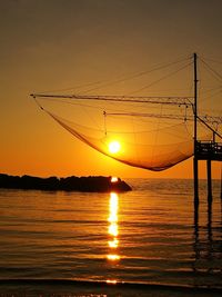 Sunset shining through fishing net over sea