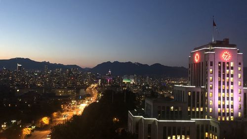 Illuminated buildings in city against clear sky at night