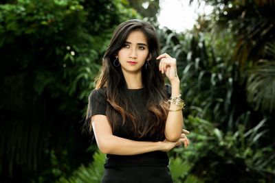 Beautiful young woman standing against trees