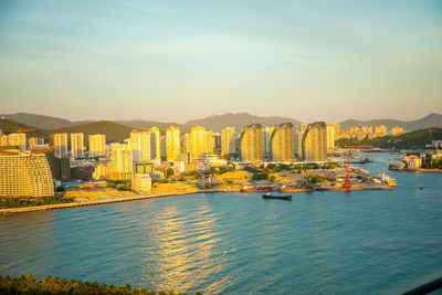 City by sea against sky during sunset