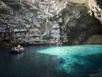 People by rock formation in boats on sea